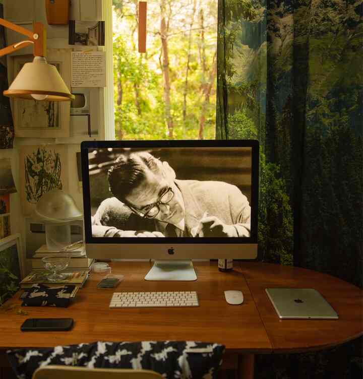 A wood tone and green home office featuring a computer and desk, creating a cozy and nature-connected atmosphere