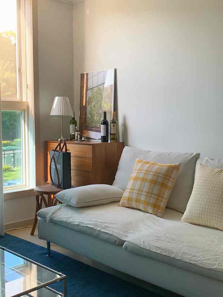 Living room with white and wood tones, featuring a cozy sofa and console table in a natural setting