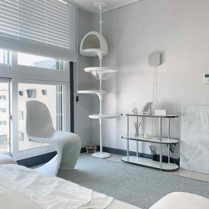 Bright and clean white-toned living room featuring a central-right cat tower and chrome sideboard in a modern interior design