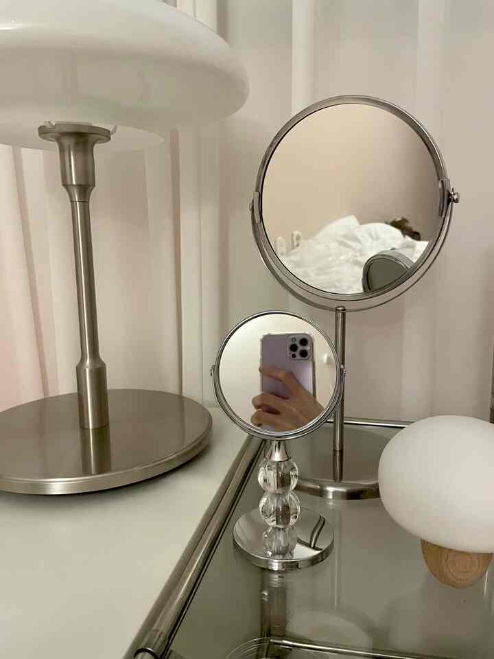 Modern interior accents featuring silver-tone mirrors and a table lamp on a reflective surface