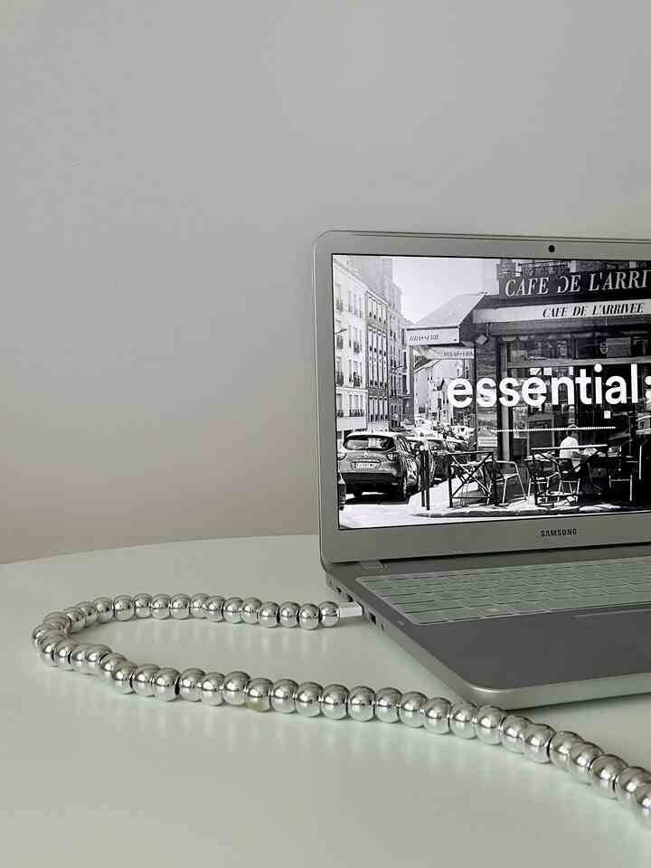 モノトーンのワンルーム空間、丸テーブルの上にシルバーのUSBケーブルとノートパソコンが置かれたシンプルなインテリア