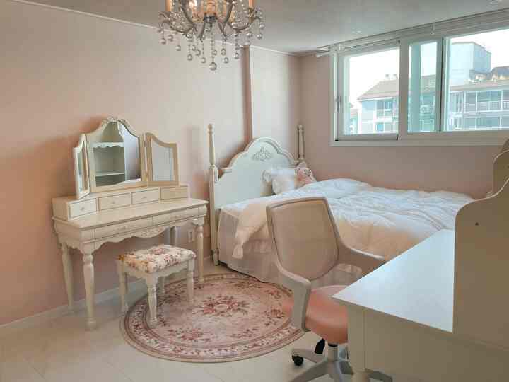 ピンク色の壁とホワイトの家具が配置されたプリンセススタイルの寝室