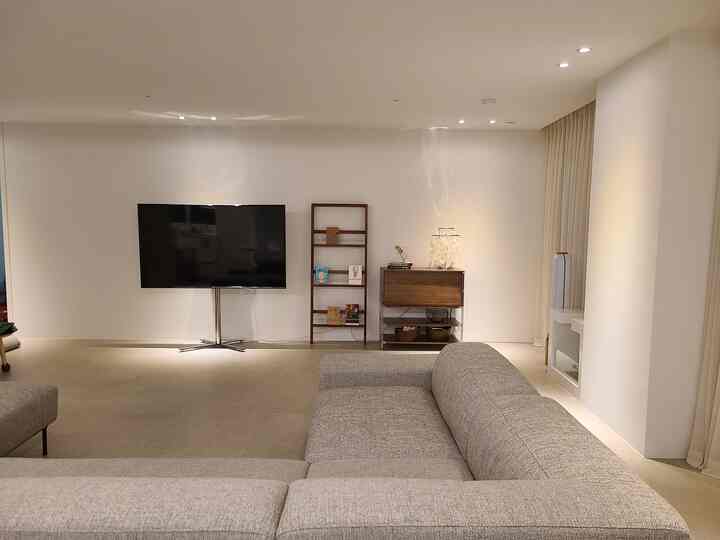 Modern natural living room with white walls and beige curtains, grey sectional sofa and TV stand arranged in a clean layout