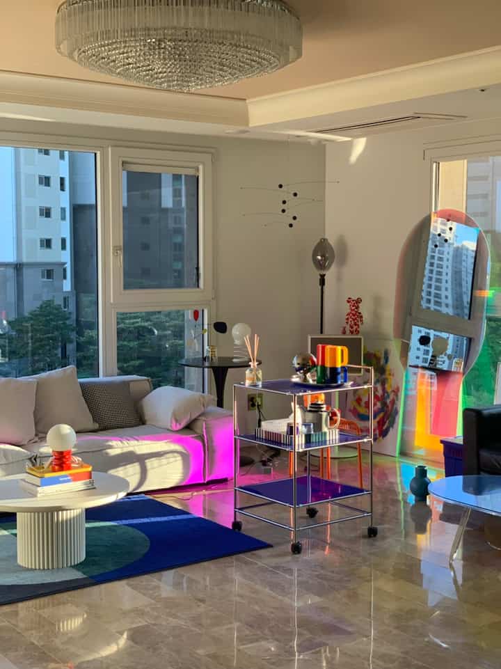 A white and navy toned living room featuring white sofa, round coffee table, and large glass mirror creating a modern atmosphere