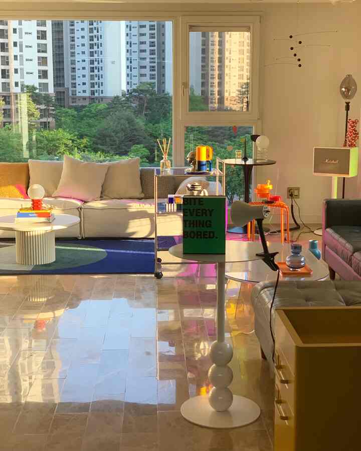 A warm beige-toned living room featuring comfortable sofas, a vibrant blue rug, and distinctive lighting elements creating a cozy atmosphere