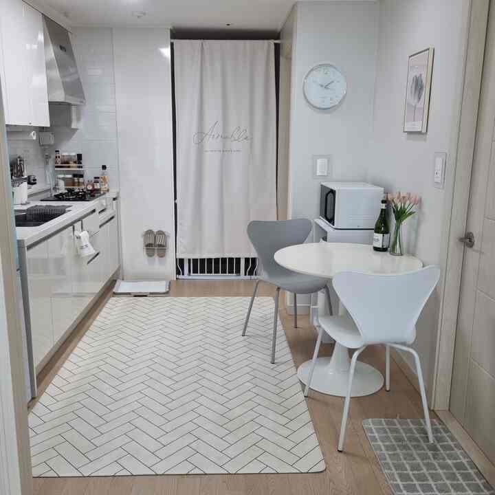 White and natural-toned kitchen space featuring round dining table and modern chairs neatly arranged