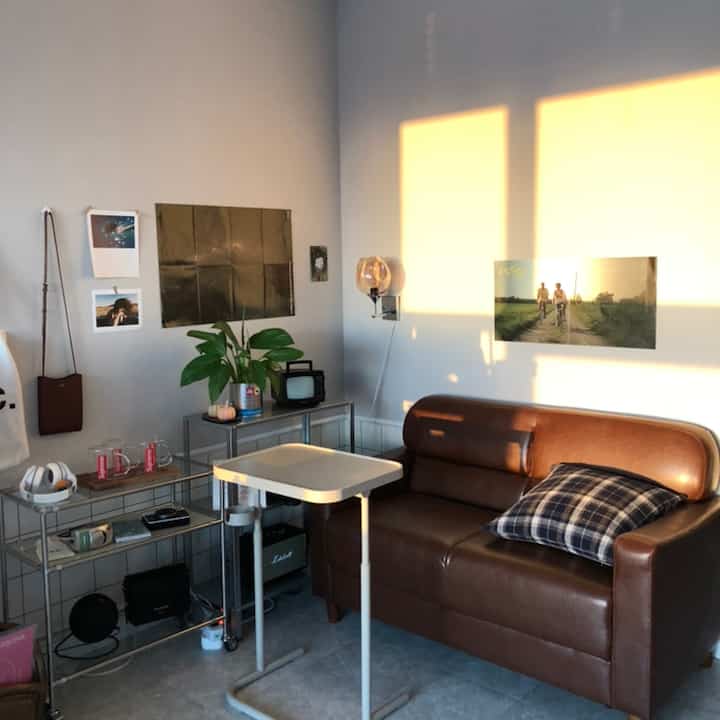 Warm beige wall and brown leather two-seater sofa with wall sconce in a modern living room space