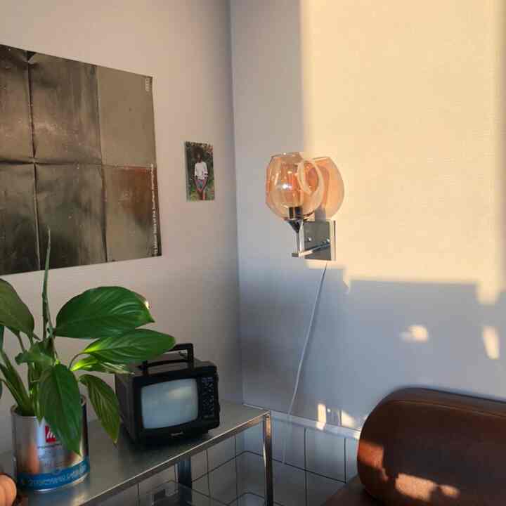Minimal living room with warm brown leather sofa and silver stainless table, featuring Burgundy wall sconce adding cozy atmosphere