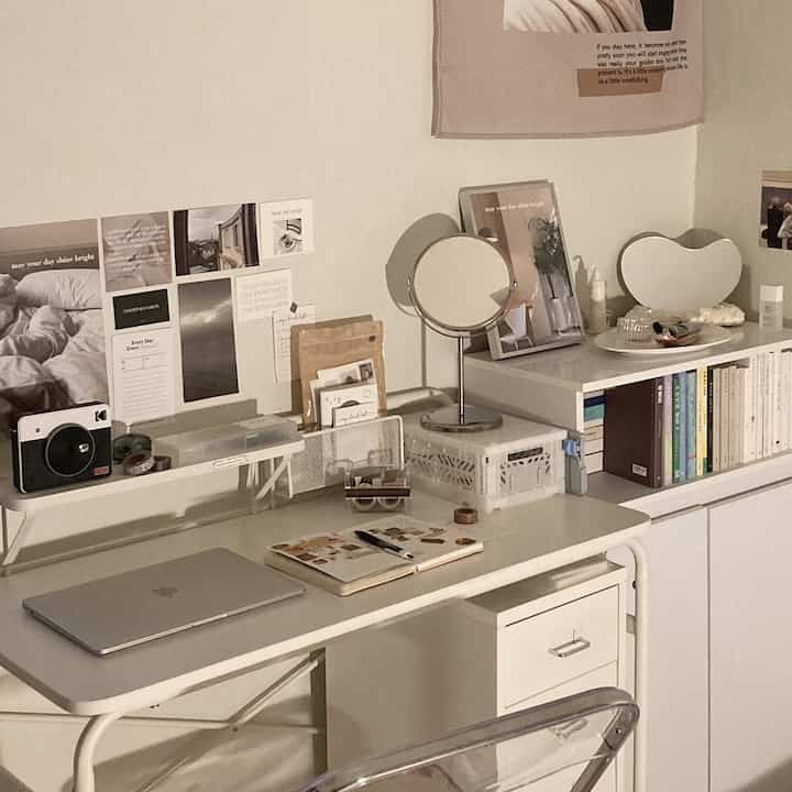 Beige and white toned study featuring a white desk, bookshelf, and transparent chair in a cozy workspace
