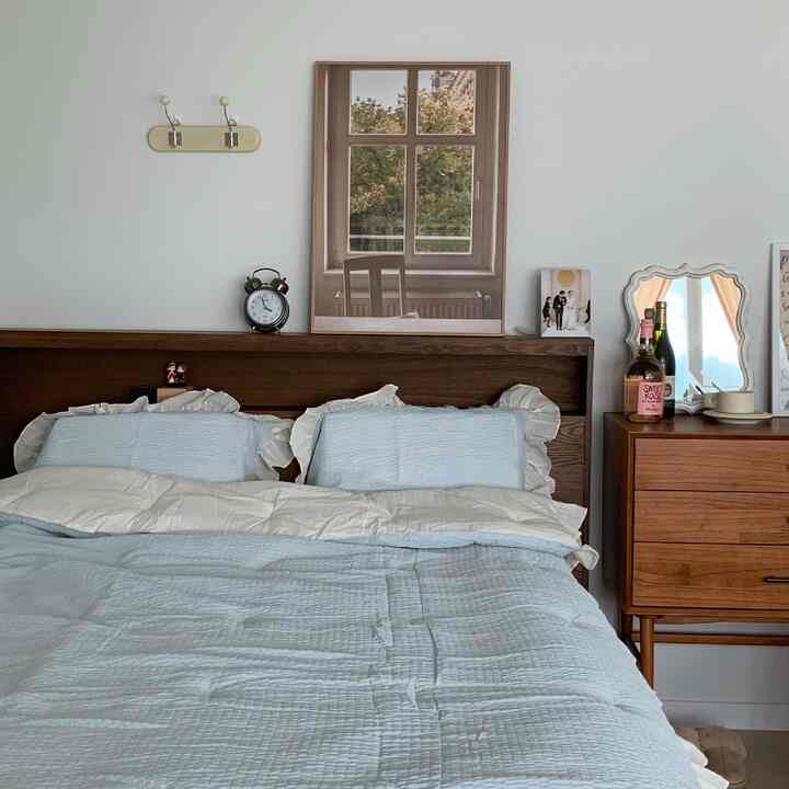Cozy blue and brown toned two-person bedroom featuring wooden headboard and nightstand in a minimal natural style