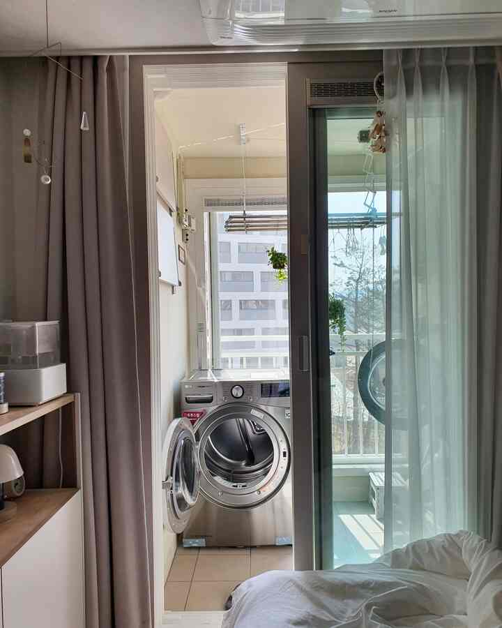 Natural-toned bedroom featuring a balcony and front-loading washer dryer, creating a cozy atmosphere