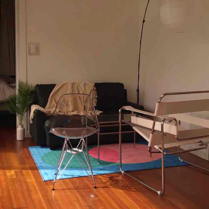 Natural-toned living room featuring a black sofa and beige armchair with a modern interior design