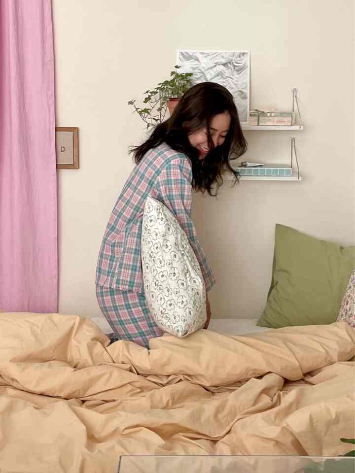 Beige and pink toned bedroom featuring bedding and cushions in a cozy studio apartment interior