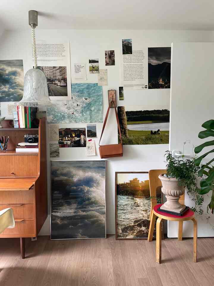 Natural-toned living room with wood flooring, wooden furniture, and various sea and nature-themed posters decorating the wall creating a simple atmosphere