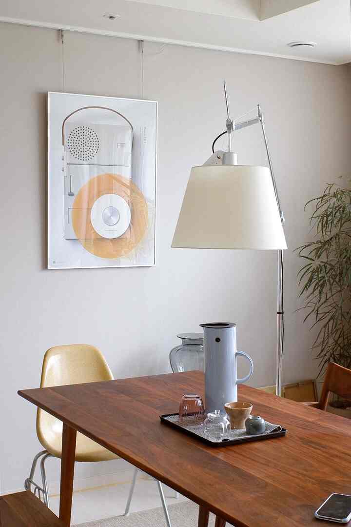 ナチュラルな色調のリビング、木製テーブルとフロアランプが配置された印象的なダイニングスペースのあるインテリア