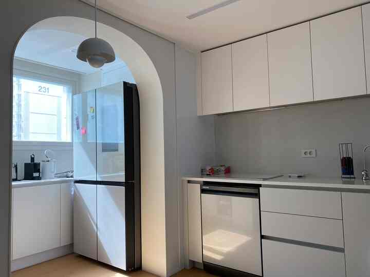 ホワイトとベージュのトーンのキッチン、アーチ型の入り口とビルトイン家電が調和したモダンなインテリア