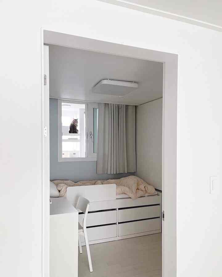 White toned kids' room featuring a desk and storage bed arranged minimally with a clean atmosphere