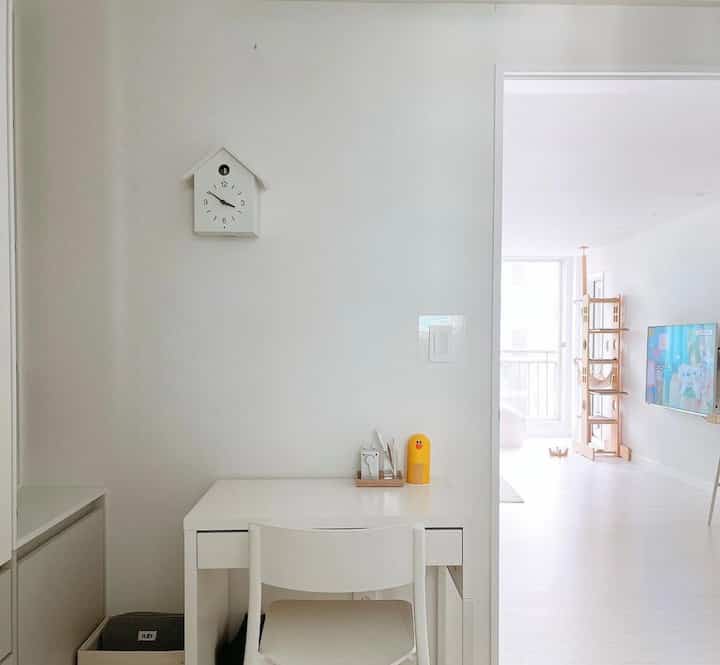 White and natural toned small room connected to living room featuring a cat tower and a clean home office setup