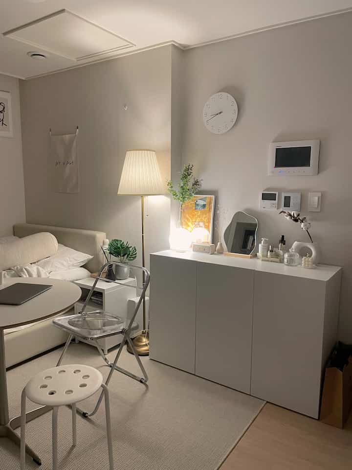 White and beige tone studio living room featuring sofa bed and warm lighting with a clean cozy atmosphere