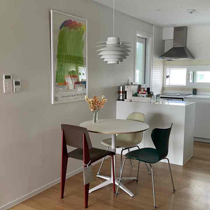 White and wood tone dining room featuring mid-century modern dining table with three dining chairs centrally placed