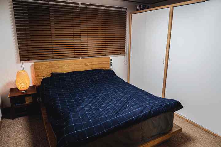 Natural-toned bedroom featuring wood blinds and navy bedding with a cozy atmosphere