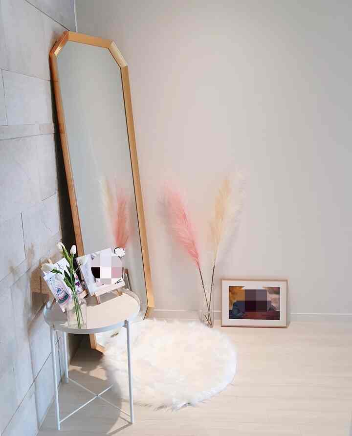 白とゴールドの玄関ホール、金色のフレームの鏡とピンクのパンパスグラスが配置された雰囲気のあるインテリア