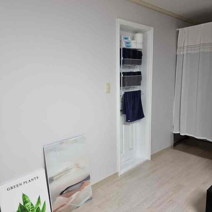 Bright white and natural toned entrance featuring a lace curtain and minimal towel rack for a clean atmosphere