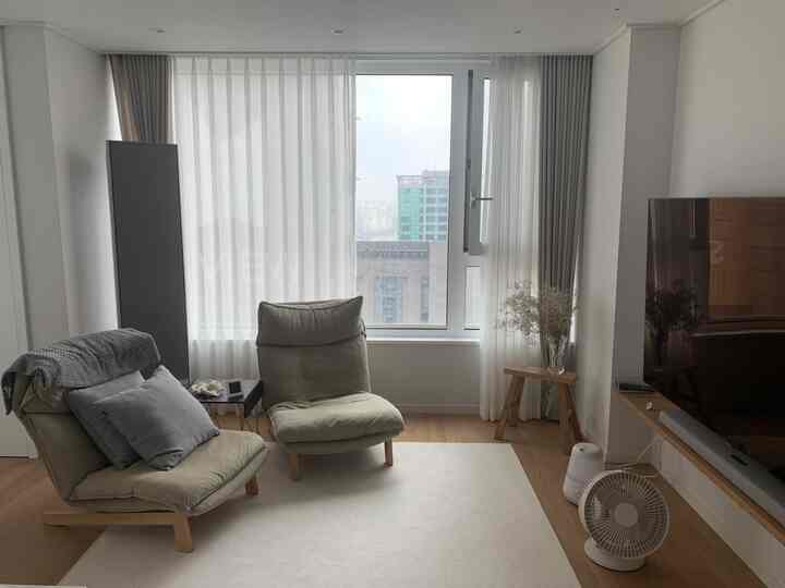 A white and beige toned living room featuring recliner sofas and spacious carpet area with a modern, natural interior atmosphere