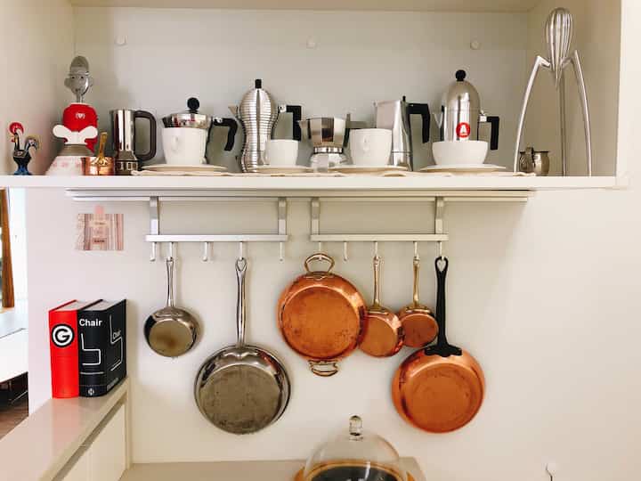 A modern kitchen with white-tone shelves neatly organized with coffee makers and kitchen utensils