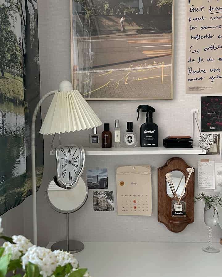 White-toned studio workspace featuring a melting clock, posters, and a table lamp in a simple setting