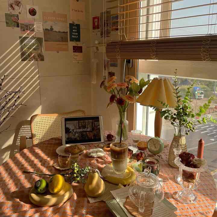 Warm beige and orange toned living room space featuring tablecloth, coffee setup, vases, and lamp creating a cozy atmosphere