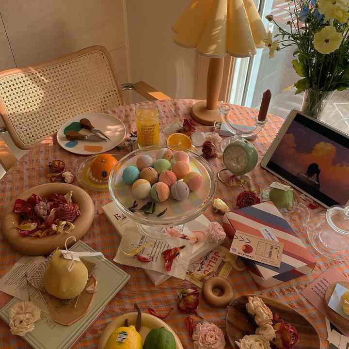 Warm orange-toned round dining room featuring wood armchair, colorful macarons, vases, and lighting creating a cozy home cafe atmosphere