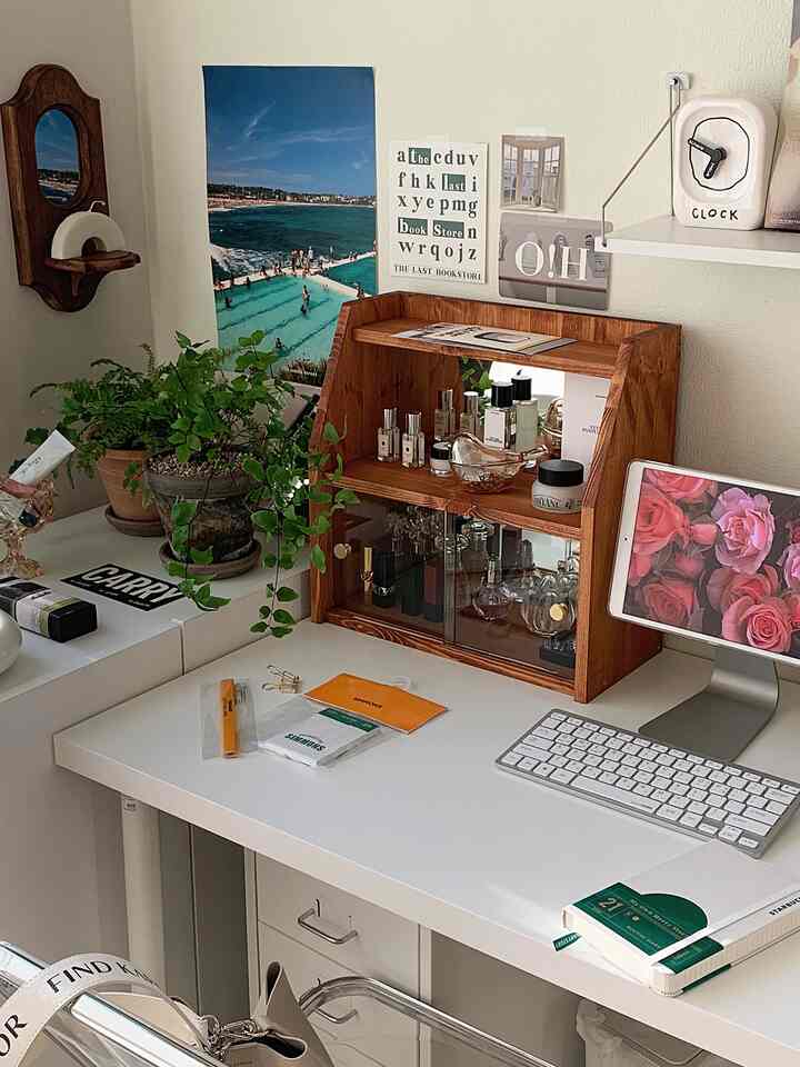 White-toned home office space featuring a white desk with drawers, a wooden organizer, and green plants creating a clean work area