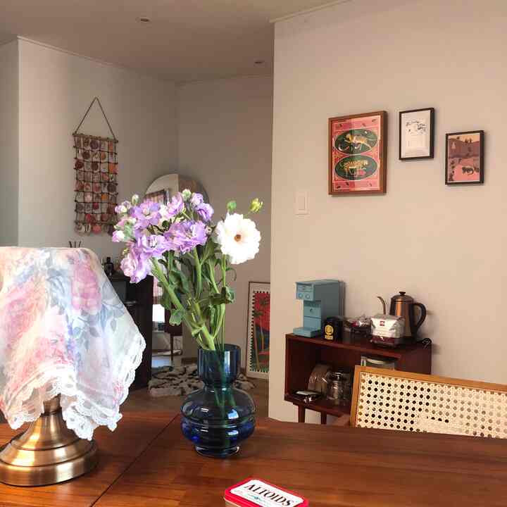 ブラウンの木製テーブルが中央に配置されたワンルーム、青い花瓶に花が飾られたナチュラルな雰囲気のあるインテリア