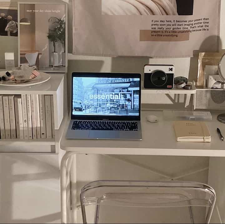 ナチュラルカラーのホームオフィス空間、透明な椅子と白いデスク、ポスターと本棚が落ち着いた雰囲気を演出