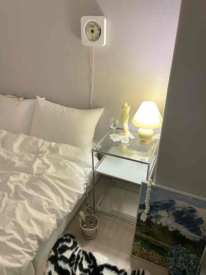 White and beige toned bedroom featuring a nightstand with warm lamp light and decorative objects creating a cozy atmosphere