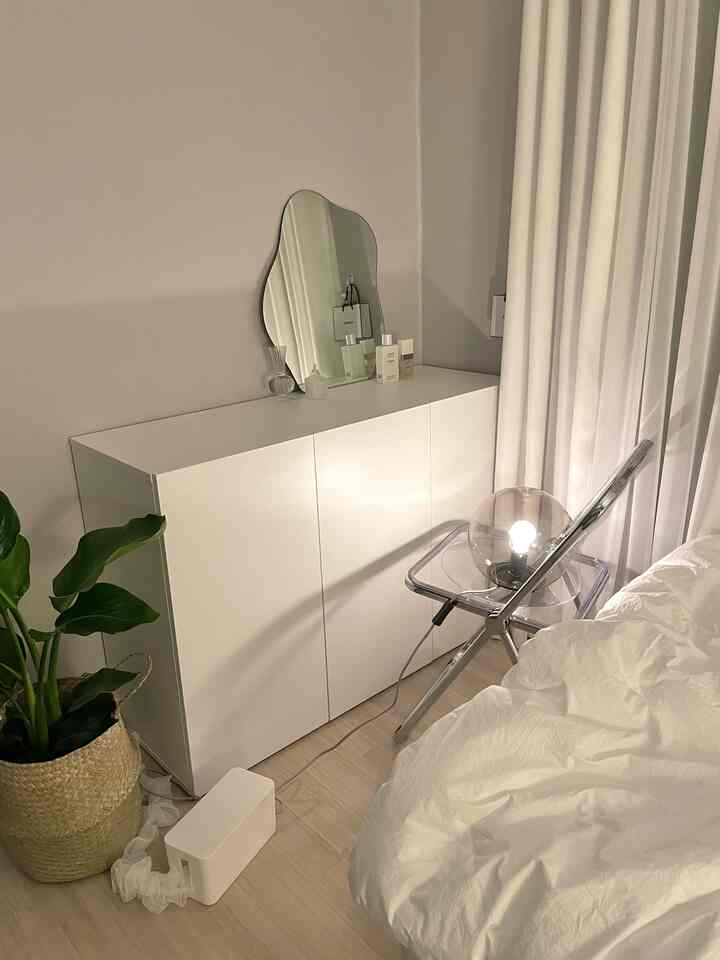 White and natural color bedroom featuring a transparent chair with a moon lamp and a uniquely shaped mirror, creating a simple and serene space
