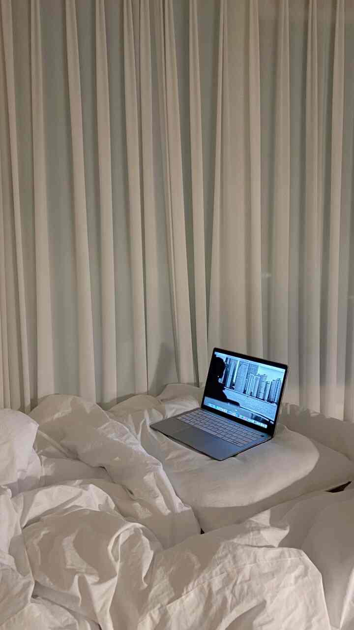 白色トーンの寝室、しわのある寝具とカーテンが配置されたシンプルで落ち着いた雰囲気のインテリア