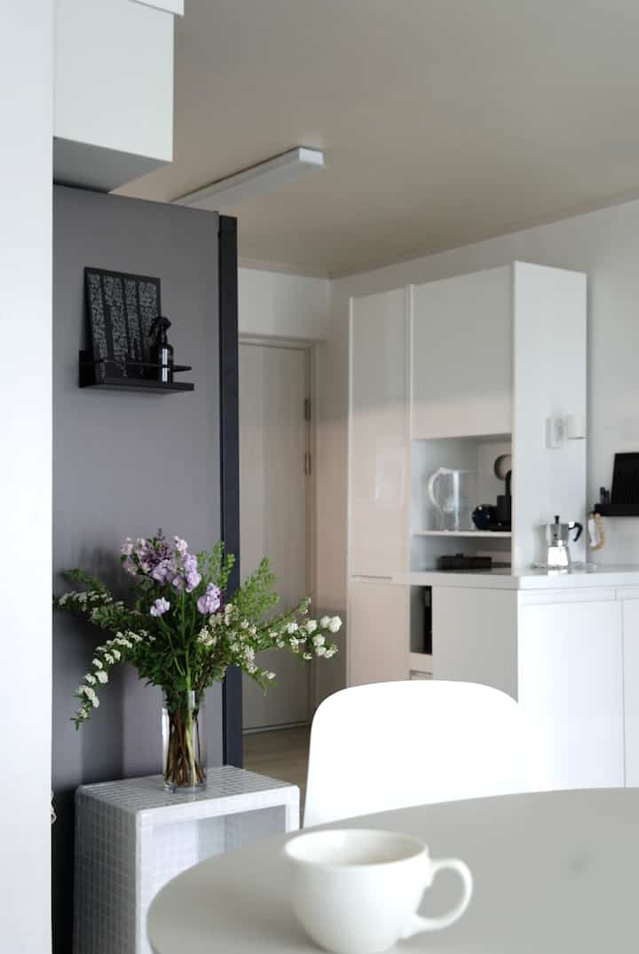 White and gray toned kitchen with a vase of flowers on center-left, bright and clean modern space