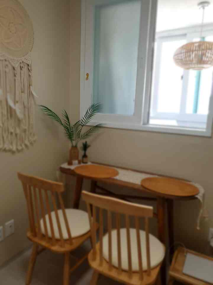A cozy small dining space in beige and natural wood tones featuring rattan vase and dreamcatcher in bohemian style