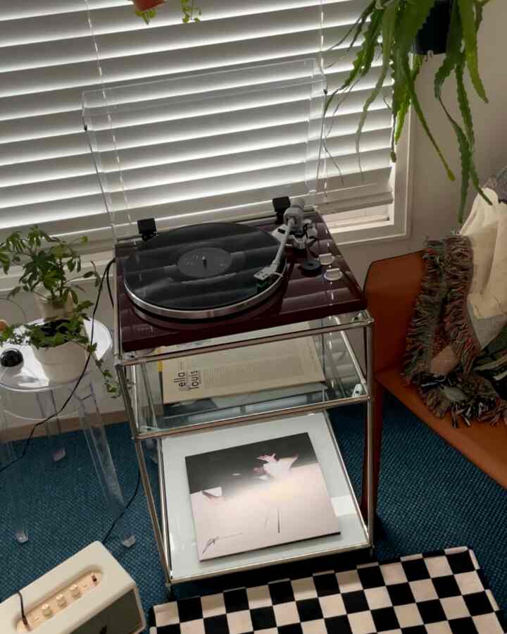 Modern living room with white blinds, featuring a turntable and brown sofa in a cozy setting