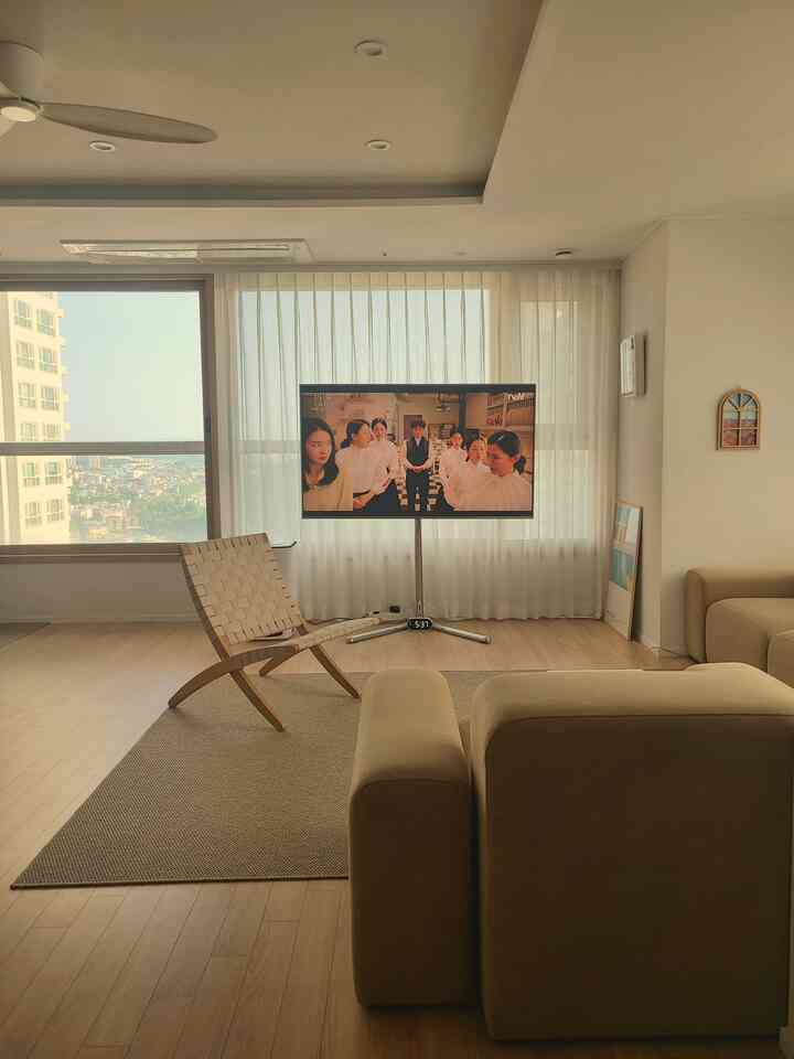 Beige and wood tone living room featuring central TV stand and comfortable sofa with a natural atmosphere