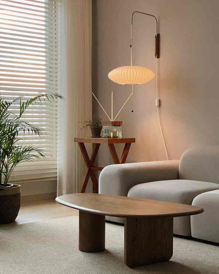 ナチュラルなベージュ色調のリビング、木目調のコーヒーテーブルとサイドテーブルにディフューザーが配置された温かみのある落ち着いた空間