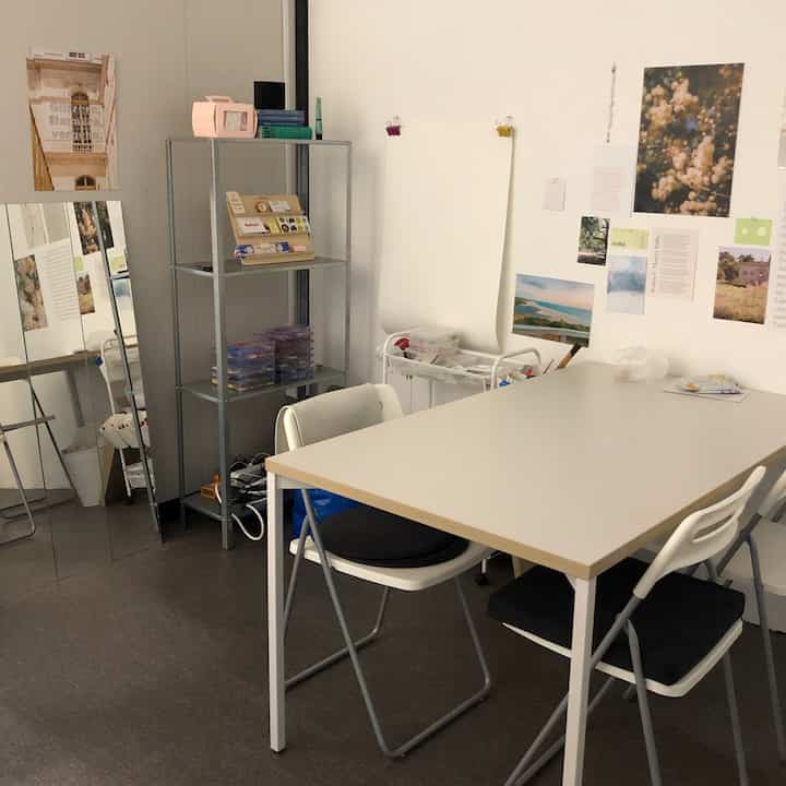 White and gray toned small home office featuring a simple desk, chairs, and shelving units creating a neat workspace