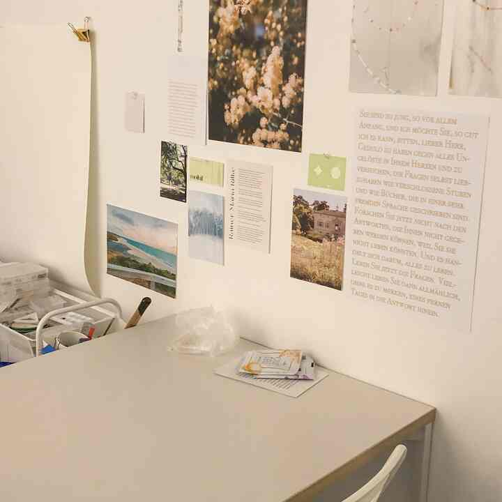 ホワイトトーンのワークスペース、壁に多彩なポスターが飾られ、シンプルなデスクが配置された雰囲気のあるインテリア