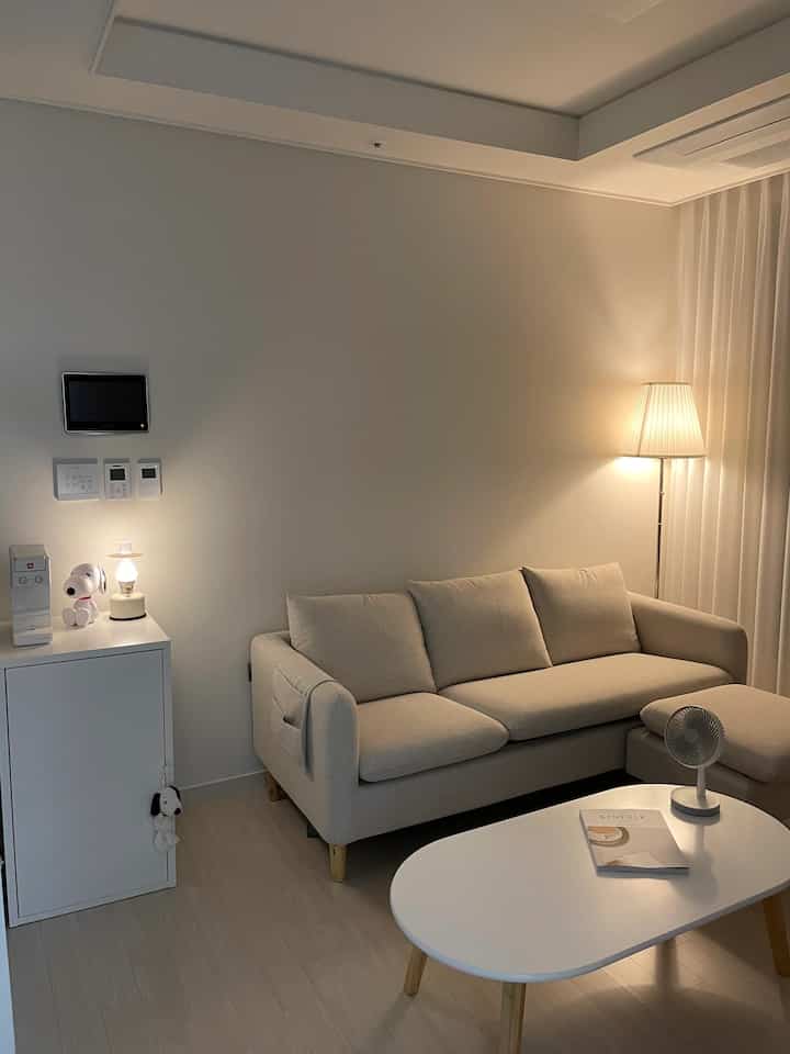 Modern two-person living room with beige sofa and white coffee table in a white-toned setting