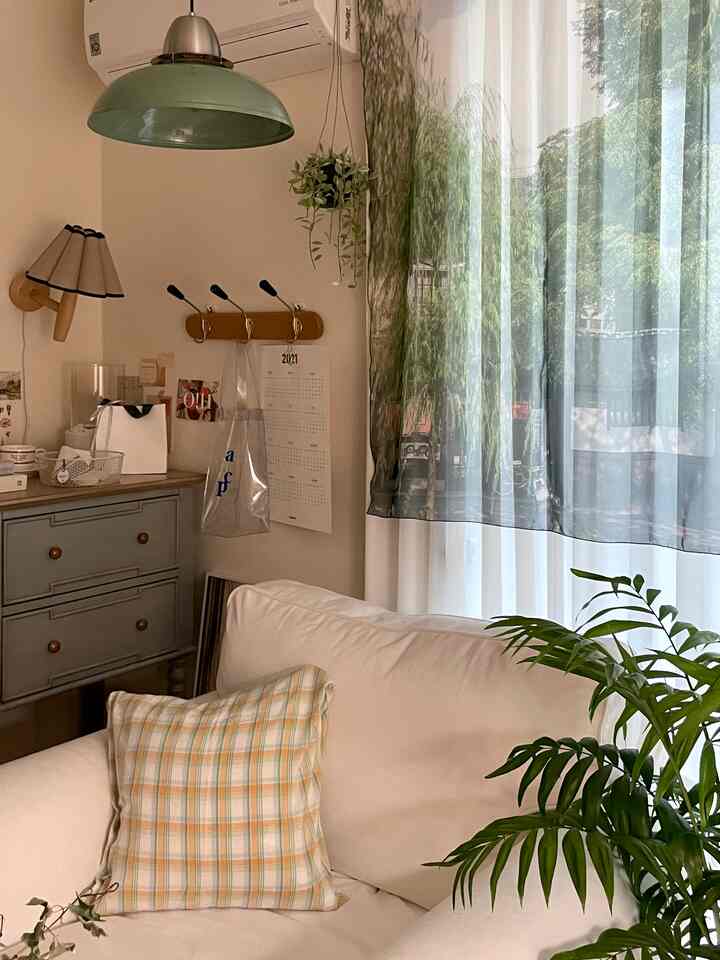 ナチュラルな色調のリビング、白いソファと植物、ヴィンテージ家具が配置された落ち着いた雰囲気の空間