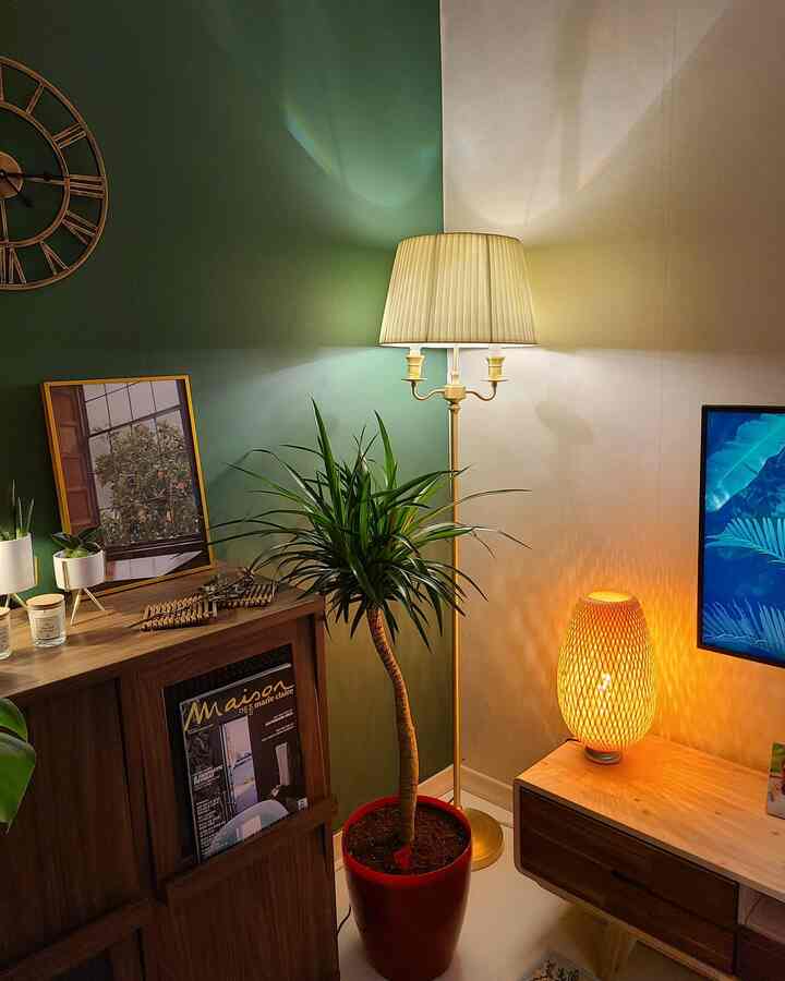 Living room corner with green walls and wood-tone furniture, featuring floor and table lamps emitting warm lighting ambiance