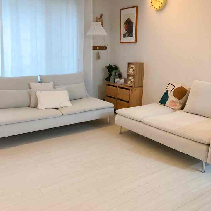 Beige and white toned living room featuring beige sofas and wooden dresser in a clean, natural space