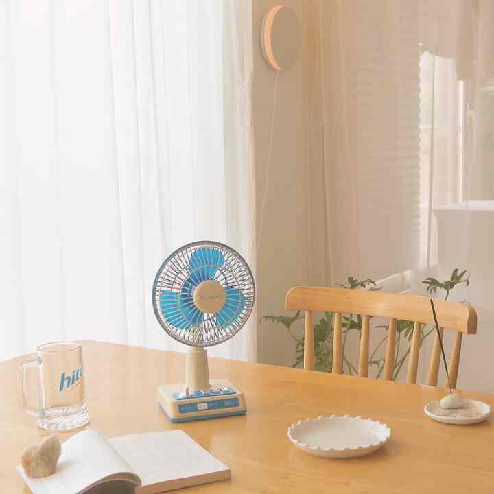 A warm wood-toned dining space with white curtains, featuring a retro-style wireless fan adding an analogue vibe